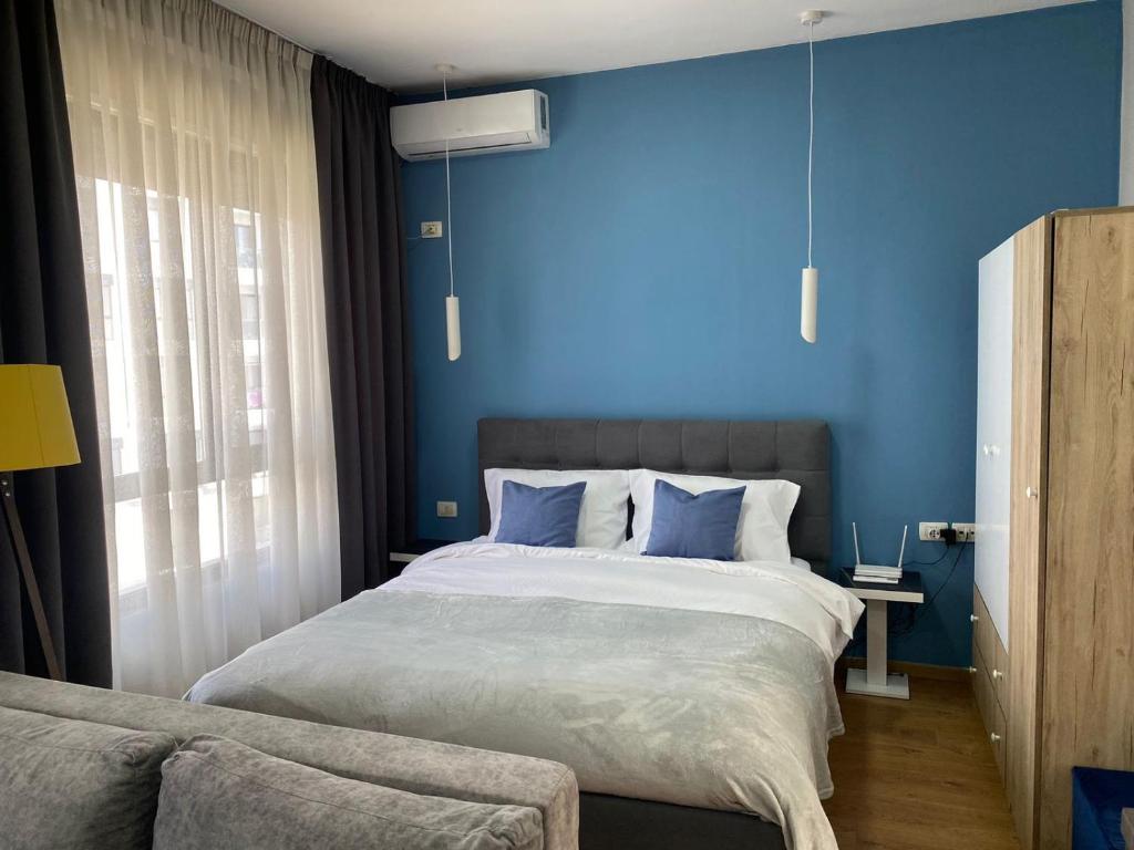 1 dormitorio con 1 cama grande y paredes azules en DM Apartments, en Tirana
