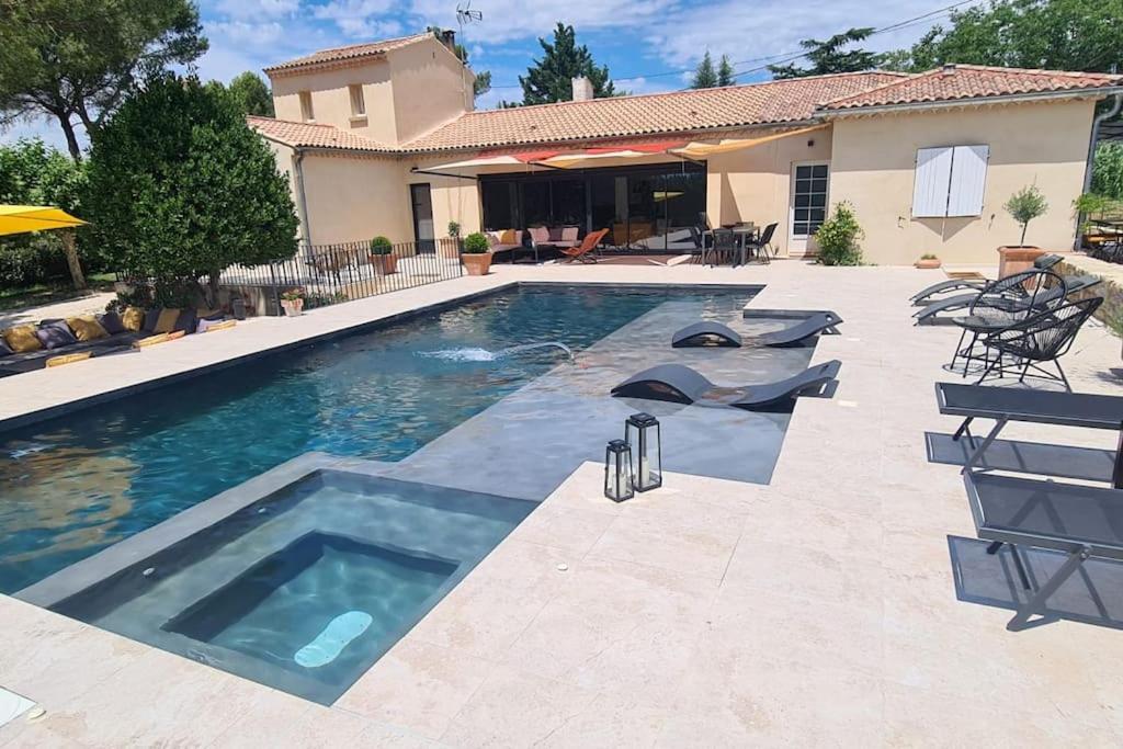 une piscine avec des chaises et une maison dans l'établissement Thaliana, à Saumane-de-Vaucluse