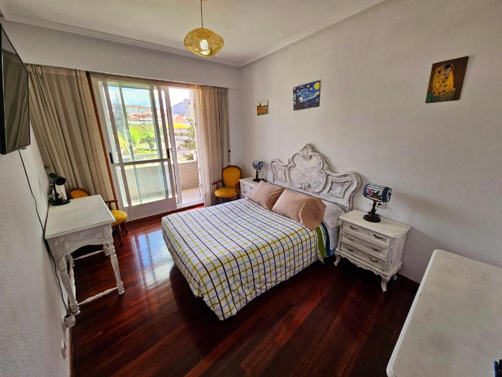 a bedroom with a bed and a table and a window at Pirámides Ourense in Ourense