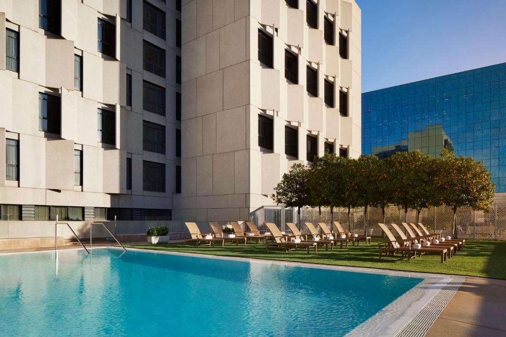 a swimming pool with lounge chairs in front of a building at NH Collection Sevilla in Seville