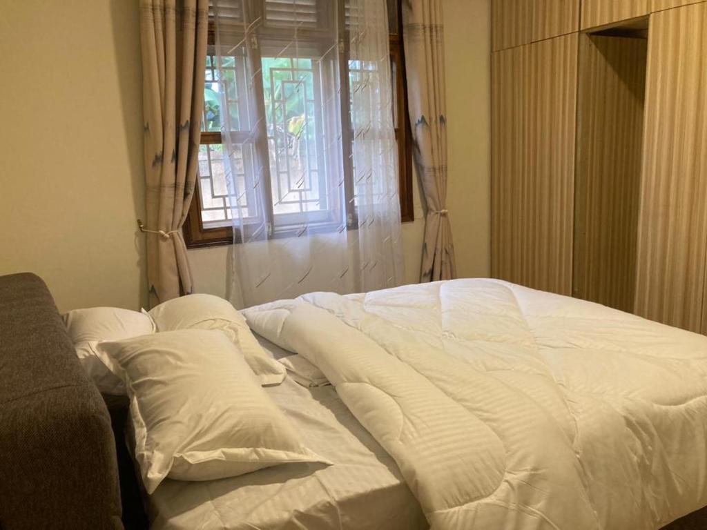 an unmade bed in a room with a window at RH4A Jinja Apartment Airport in Jinja