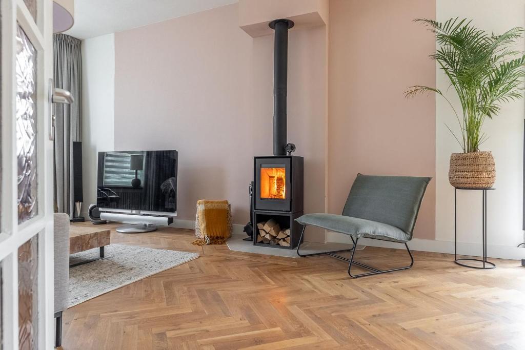 a living room with a fireplace and a chair and a tv at Luxe vakantiewoning dichtbij strand in Vlissingen in Vlissingen