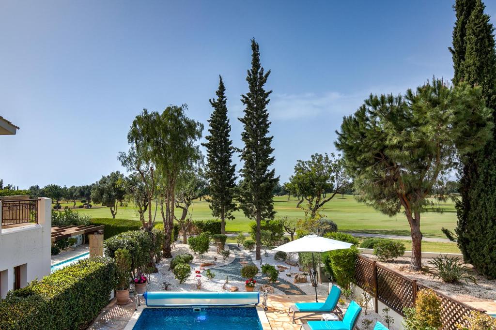 a view of a pool with chairs and trees at 2 bedroom Villa Loukia with private pool and gardens, Aphrodite Hills Resort in Kouklia