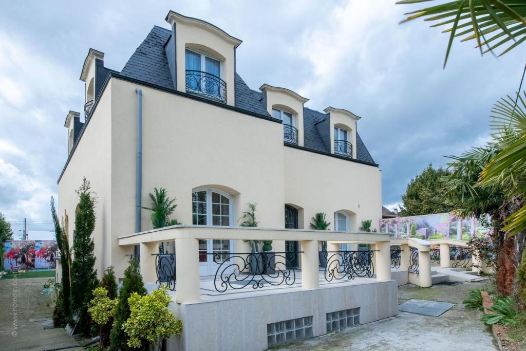 a white house with a black roof at Appartement tout confort - Paris à 10 min - tout équipé - salle de jeux in Deuil-la-Barre