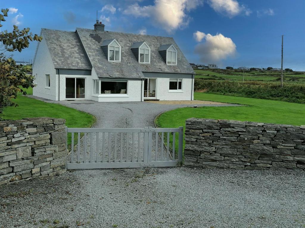 a white house with a gate and a stone wall at El Martins in Miltown Malbay