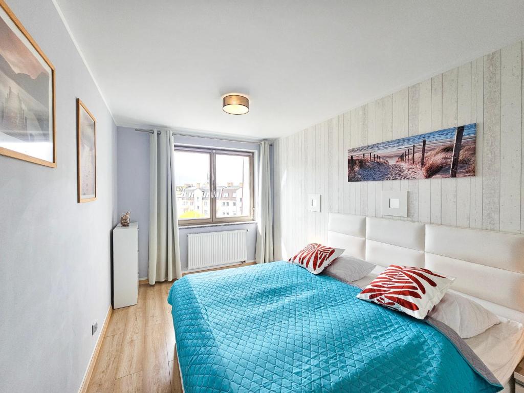 een slaapkamer met een blauw bed en een raam bij visit baltic - Róży Wiatrów in Świnoujście