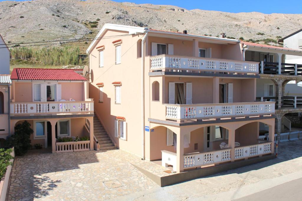 a large apartment building with balconies and a mountain in the background at Apartments Tanja & Josipa in Pag