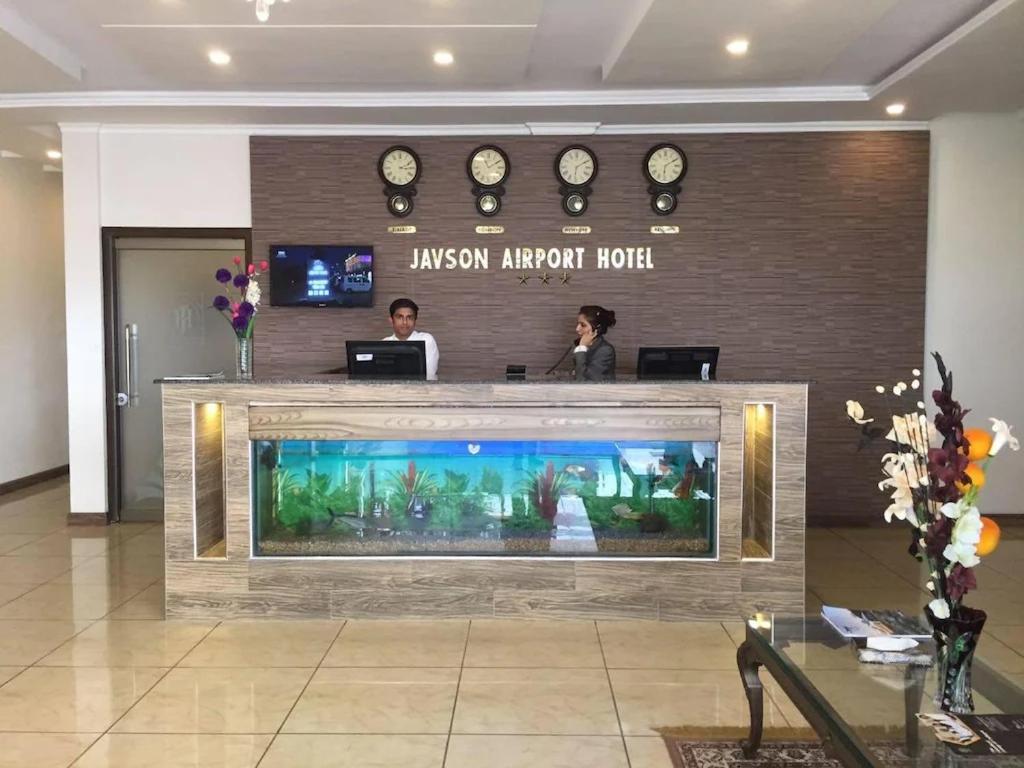 deux personnes se tenant derrière un aquarium dans un hall dans l'établissement Javson Airport Hotel, à Sialkot