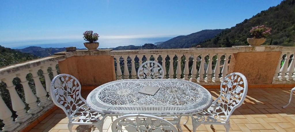 une table blanche et des chaises sur un balcon dans l'établissement L'Olivier, à Sainte-Agnès
