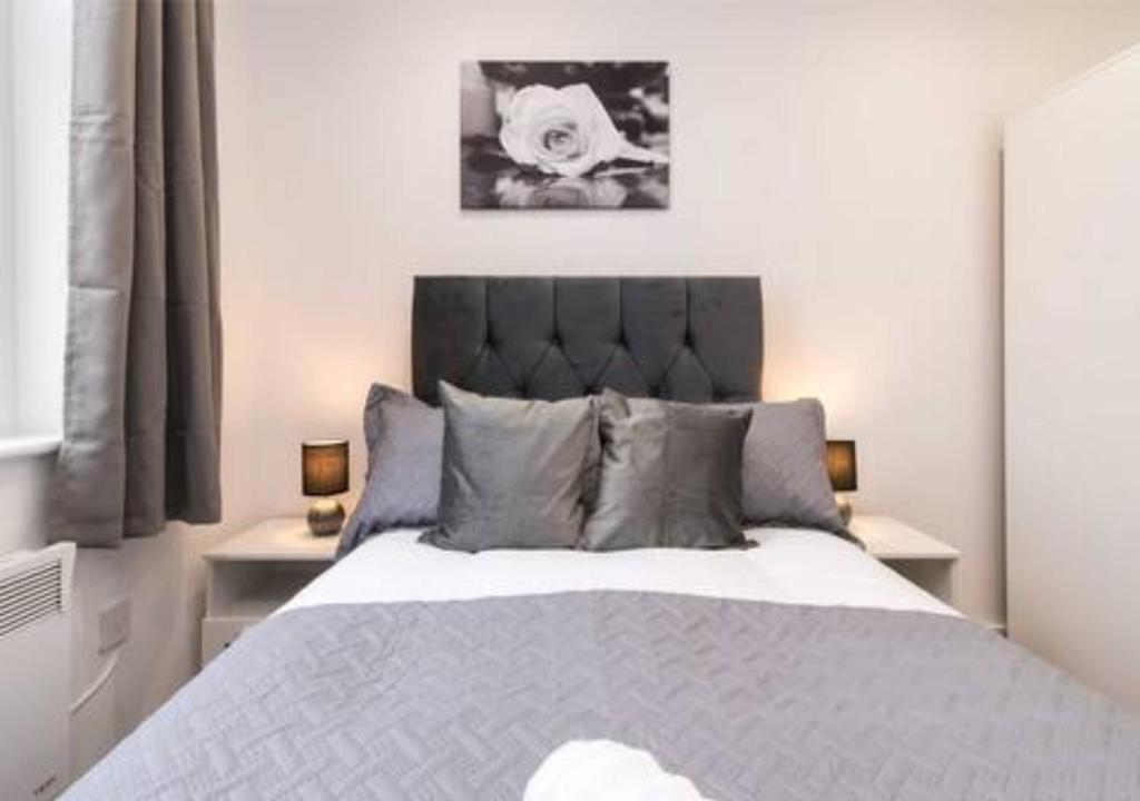 een slaapkamer met een groot bed met grijze kussens bij Webberley Stylish and Spacious Studio Unit in Stoke on Trent in Stoke on Trent