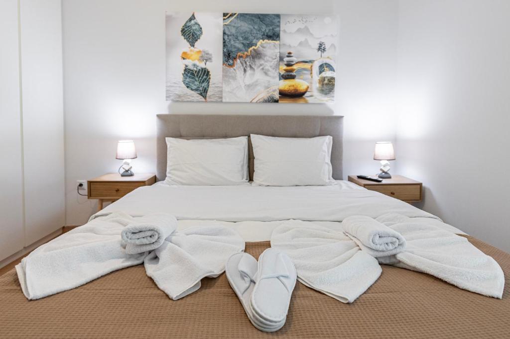 un letto con asciugamani bianchi e pantofole di Lemon Tree House Varkiza a Vari