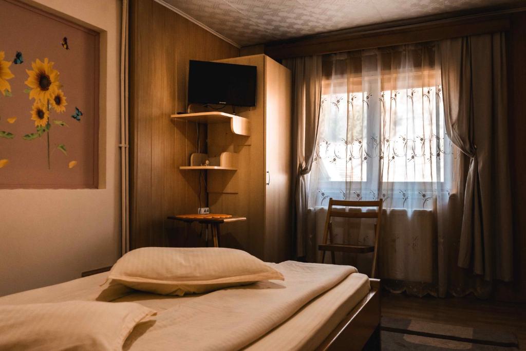 a small bedroom with a bed and a window at Pensiunea Casa Soarelui in Podu Dîmboviţei