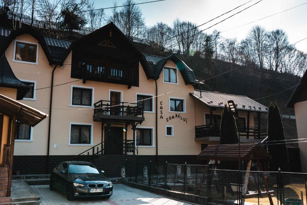 a house with a car parked in front of it at Pensiunea Casa Soarelui in Podu Dîmboviţei