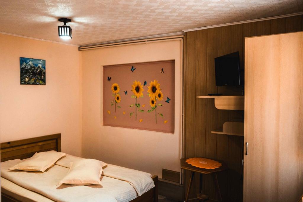a bedroom with a bed with a painting of sunflowers at Pensiunea Casa Soarelui in Podu Dîmboviţei