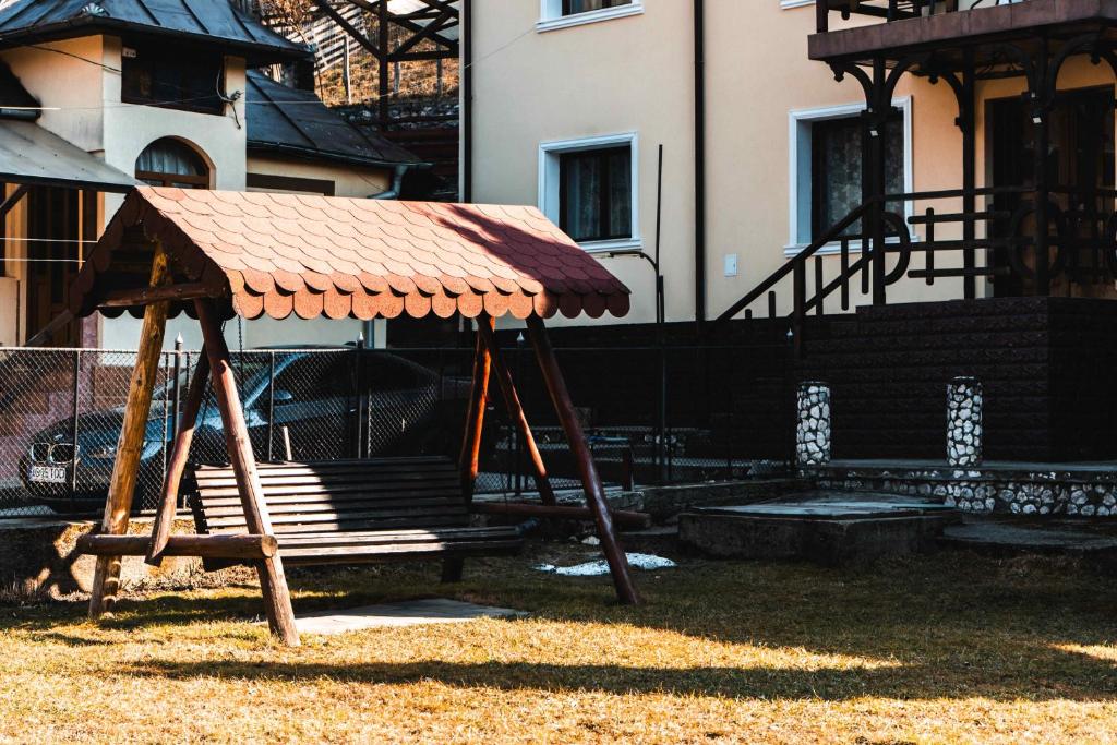 a playground with a roof and a bench in a yard at Pensiunea Casa Soarelui in Podu Dîmboviţei