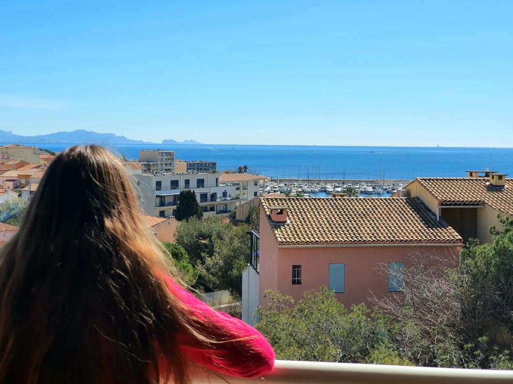 a woman looking at the city from a balcony at L'escapade Côte Bleue vue mer panoramique in Sausset-les-Pins