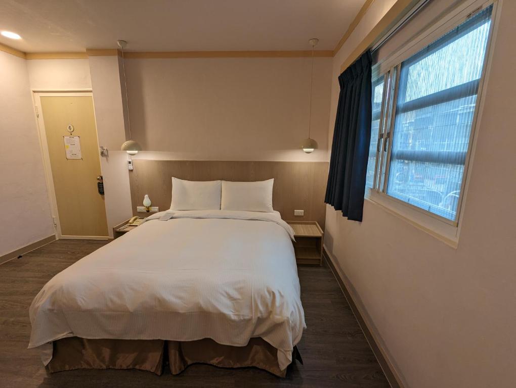 a bedroom with a large bed and a window at Kindness Hotel - Tainan Minsheng in Tainan