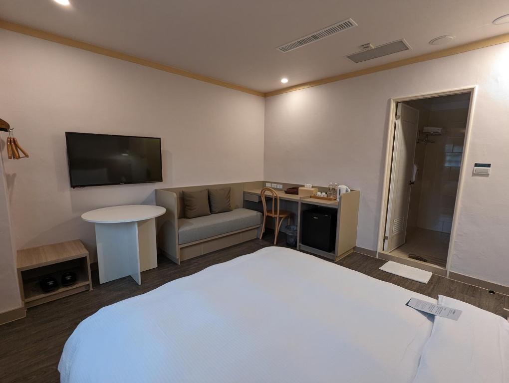 a hotel room with a bed and a couch and a television at Kindness Hotel - Tainan Minsheng in Tainan