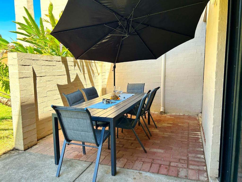 a table with chairs and an umbrella on a patio at Riverview Holiday Apartment 92 - Kalbarri WA in Kalbarri