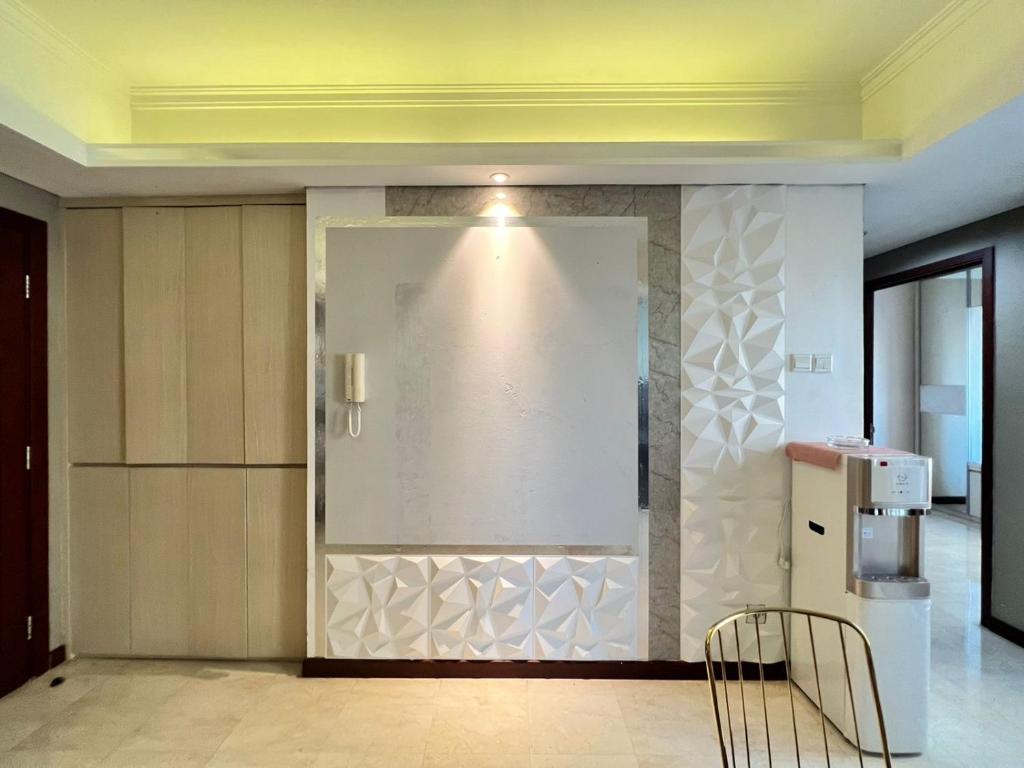 Cette chambre est dotée d'un mur blanc avec une chaise. dans l'établissement Belle’s WMR Apartment, à Jakarta