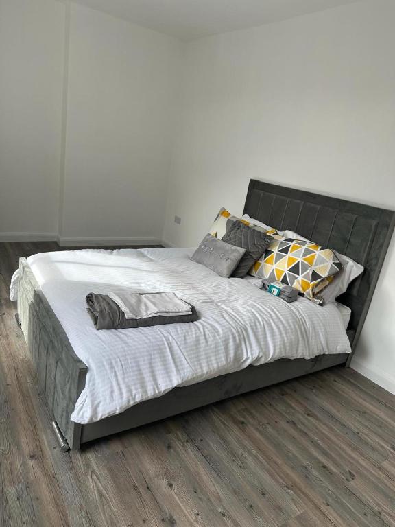 um quarto com uma cama grande com lençóis brancos e almofadas em Immaculate 1-Bed Apartment in Northampton em Northampton