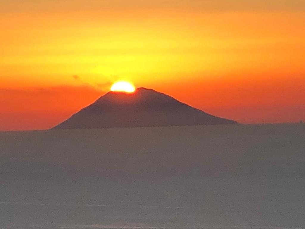 uma montanha com o pôr do sol em cima dela em BLOOM em Tropea