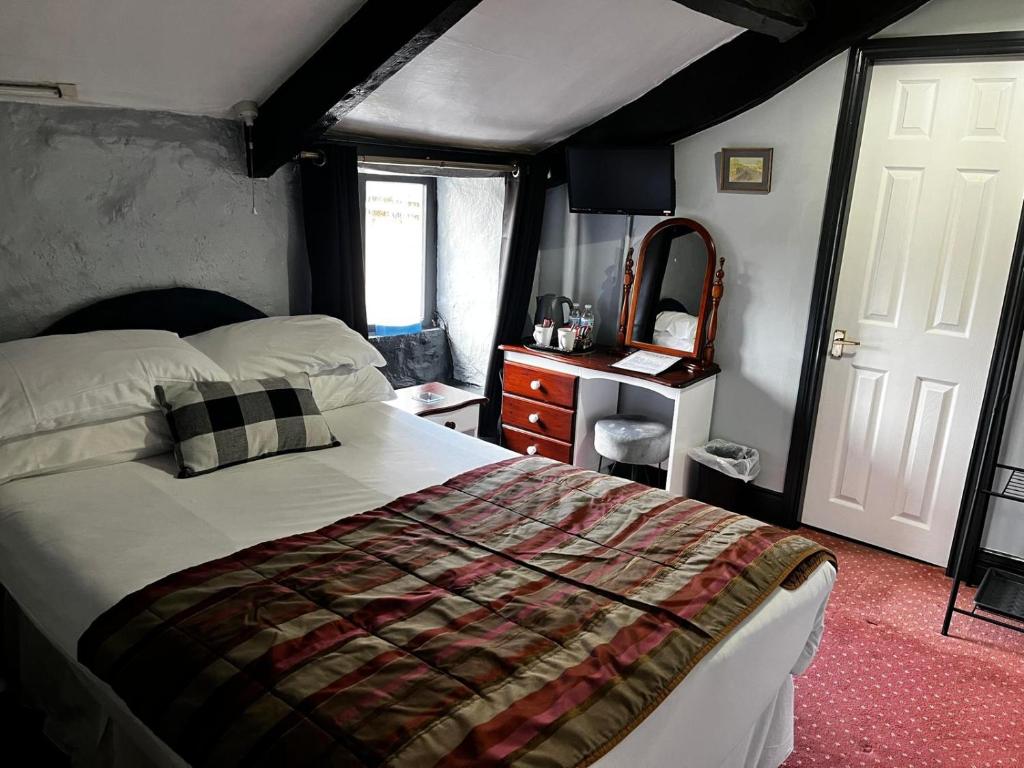 um quarto com uma cama, uma cómoda e um espelho em Black Bull Hotel em Reeth