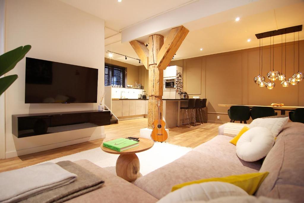 ein Wohnzimmer mit einem Sofa, einem TV und einem Tisch in der Unterkunft Stunning 2 bedroom Apt. Heart of the city! in Amsterdam