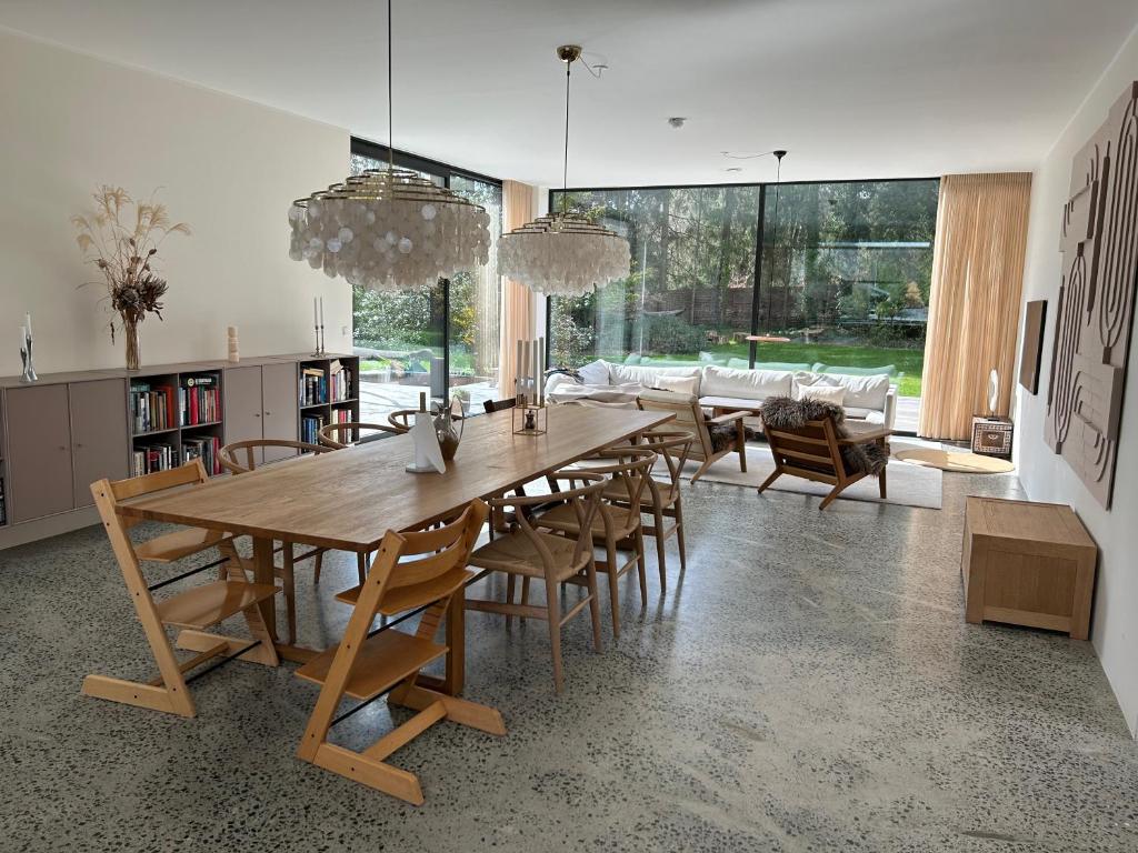 a dining room with a large wooden table and chairs at Modern bungalow in forest area in Nærum