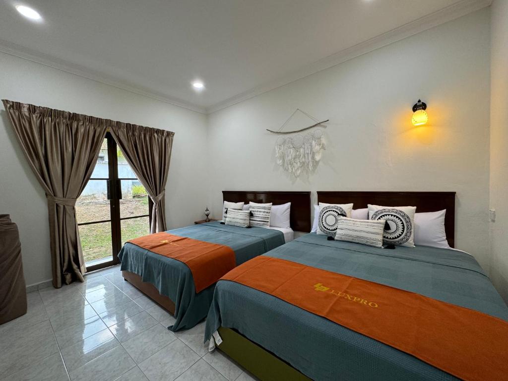 twee bedden in een kamer met een raam bij A’famosa Villa D’amour in Melaka