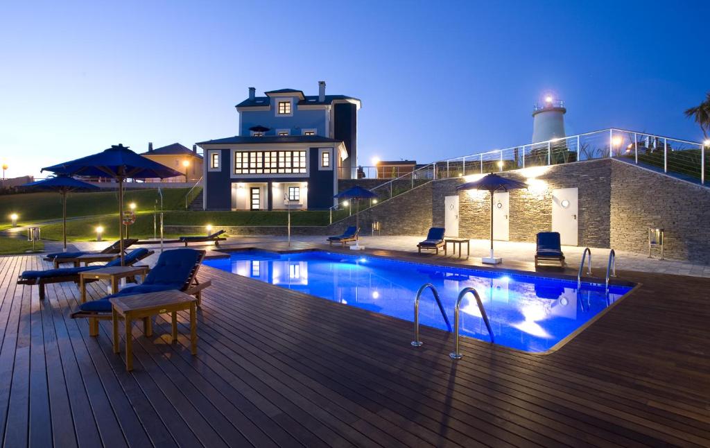 una piscina en una terraza con sillas y un edificio en Apartamentos Viavelez, en La Caridad