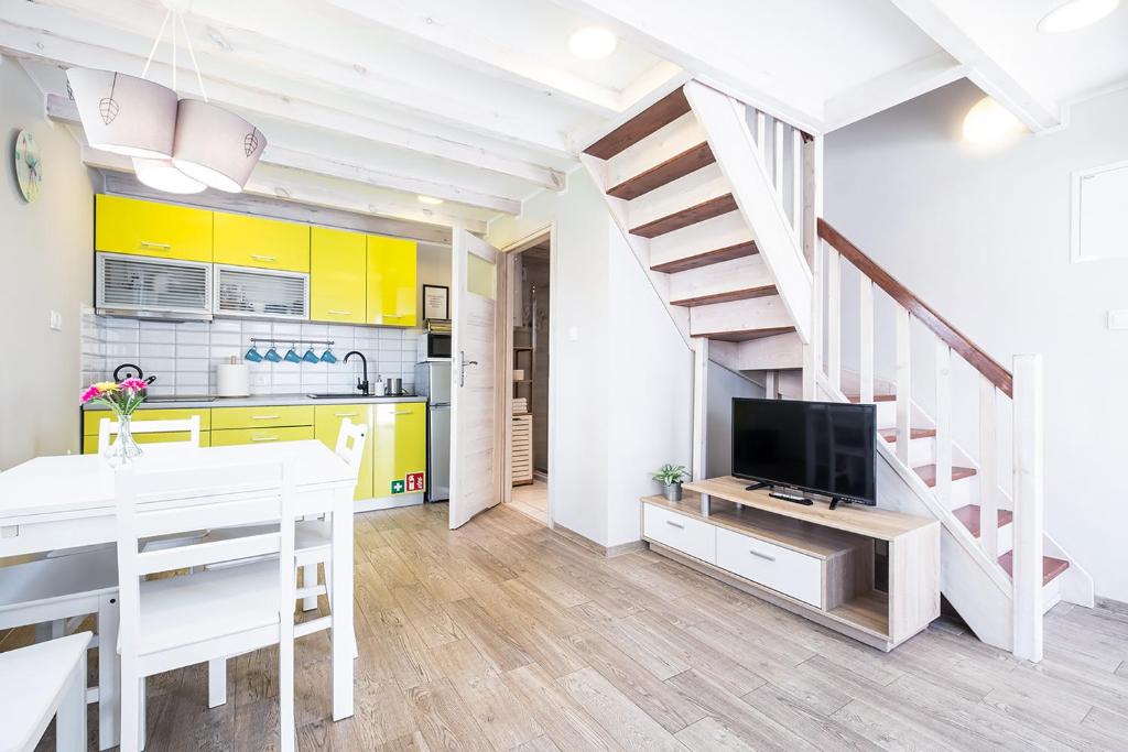 a kitchen and dining room with yellow cabinets and a television at Bedroom - domek nr 1 in Łeba