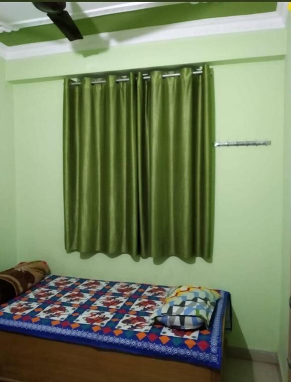 a bed in a room with a green curtain at S.S. GUEST HOUSE in Patna