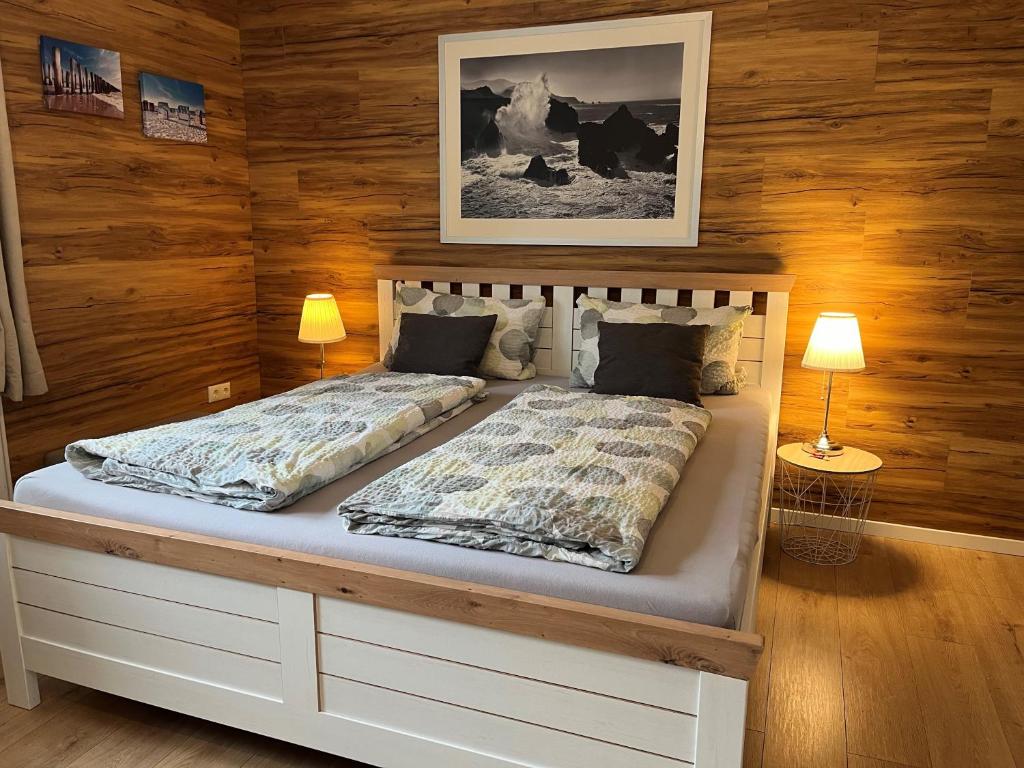 a bed in a room with wooden walls at Appartement 1 mit Küche und neuem Bad, frisch saniert in Friedrichskoog