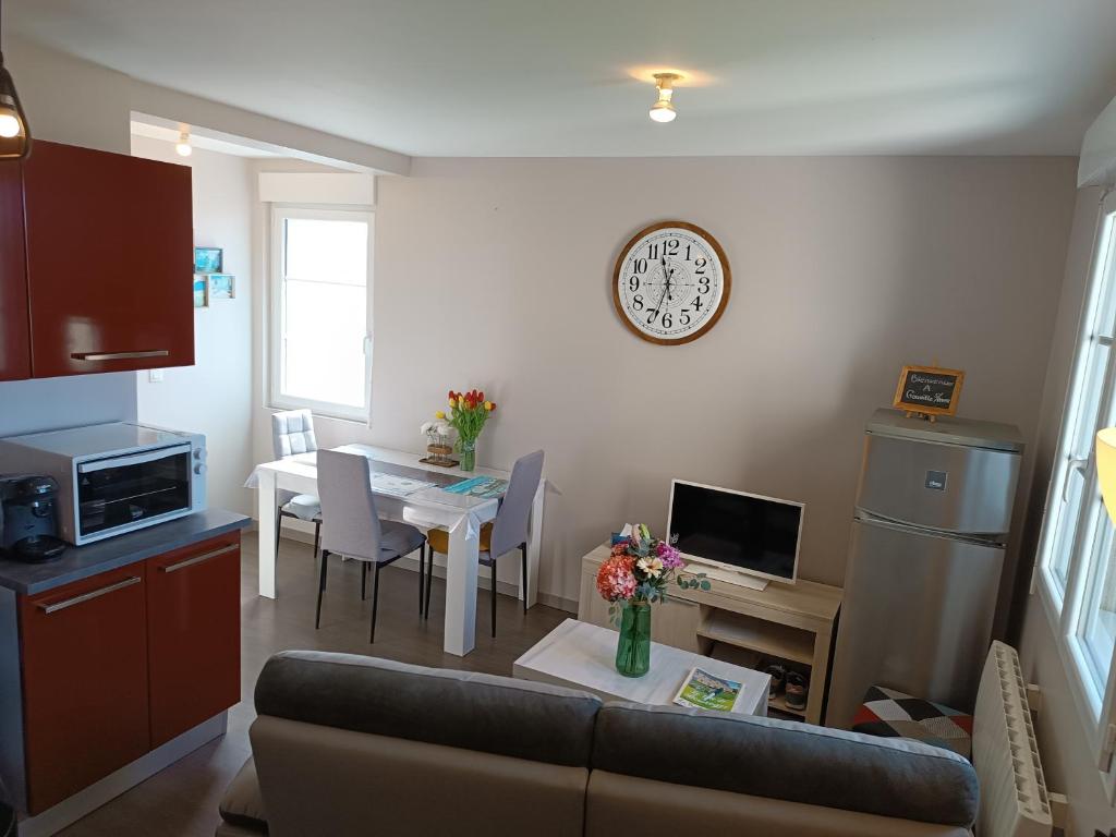 ein Wohnzimmer mit einem Sofa und einem Tisch mit einer Uhr in der Unterkunft Appartement Cosy proche Mer in Gouville-sur-Mer
