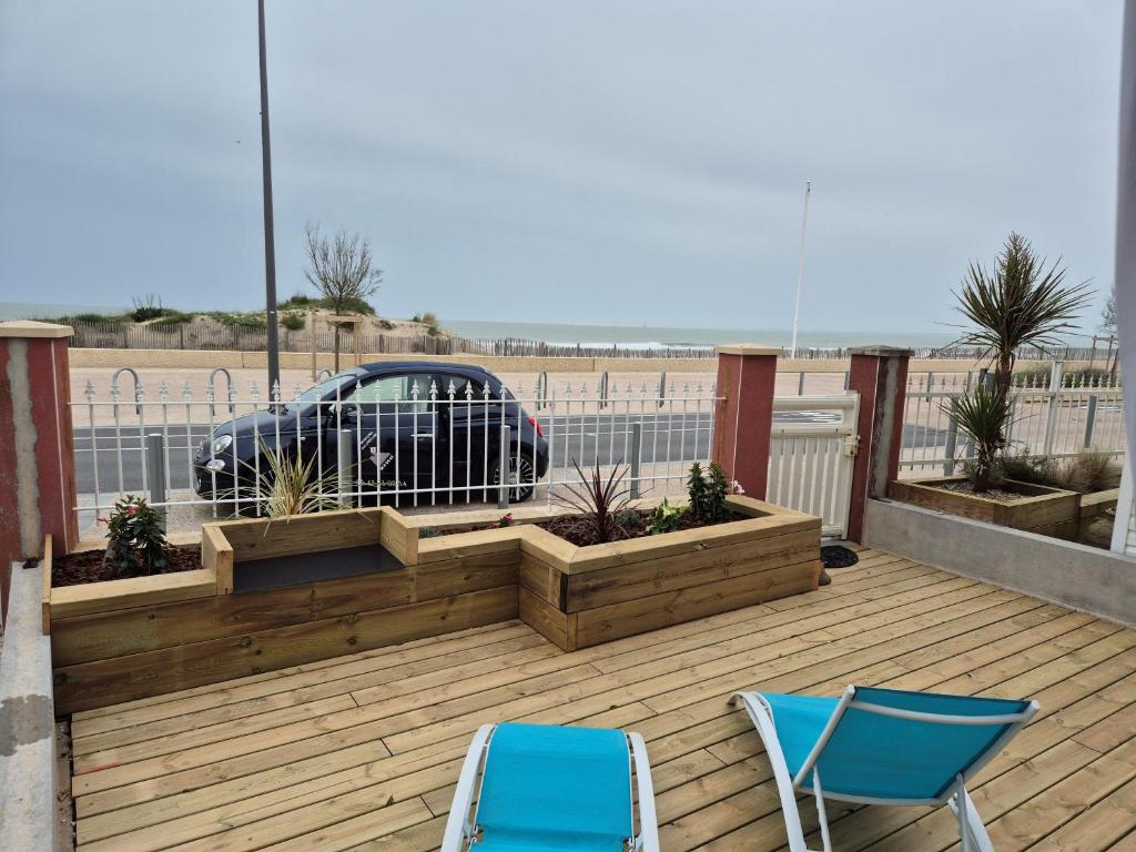a deck with two chairs and a car in a parking lot at Joussac Côté Plage - Protocole sanitaire strict in Soulac-sur-Mer