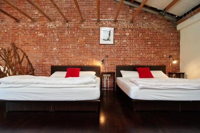 two beds in a room with a brick wall at Just For Fun B&B in Pingxi