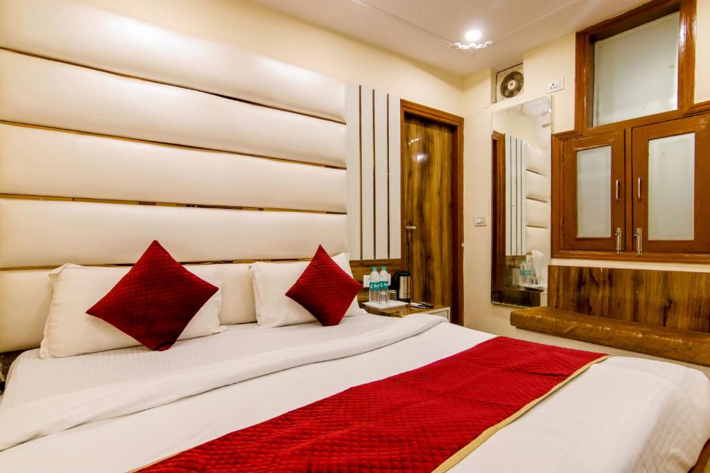 um quarto com uma cama grande e almofadas vermelhas em The Price Hotels Main Bazar Pahar Ganj New Delhi em Nova Deli