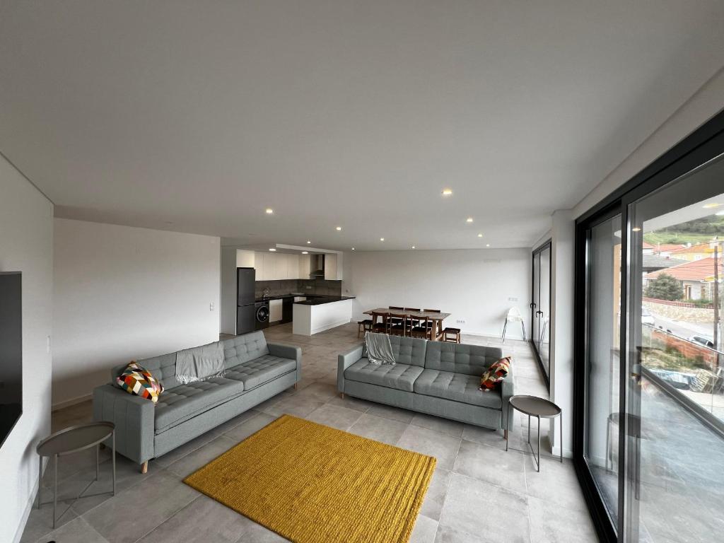 a living room with two gray couches and a kitchen at Modern spacious apartment with rooftop pool in São Martinho do Porto