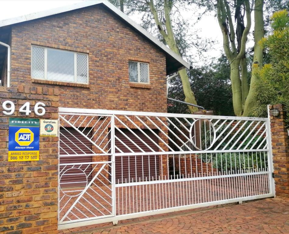 a white fence in front of a brick house at @946 in Pretoria