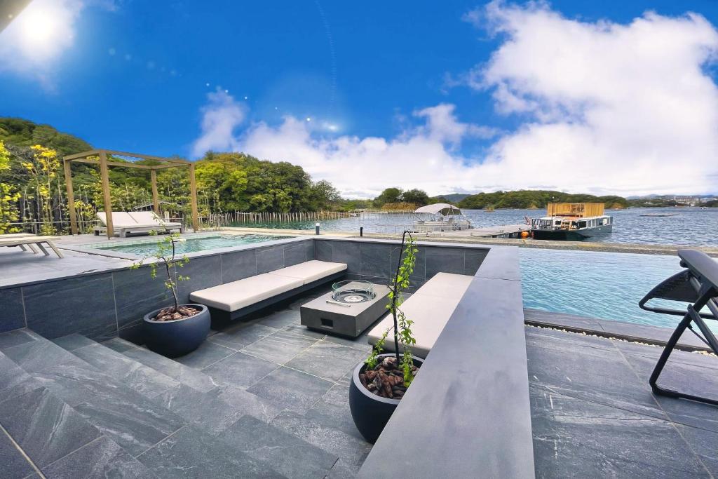 a swimming pool with two benches on a patio next to the water at MOKU ISESHIMA ーl モク伊勢志摩 lー in Shima