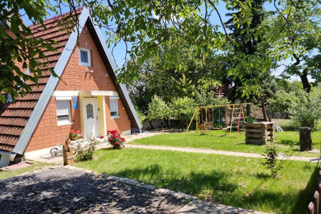 una pequeña casa de ladrillo con un parque infantil en el patio en House on Danube with Sauna - Happy Rentals en Opatovac