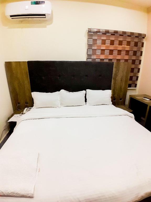 a bedroom with a large white bed with a black headboard at Come Inn Hotel in Rubuchi
