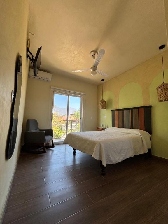 a bedroom with a bed and a chair and a window at Frutos Hotel in Ameca