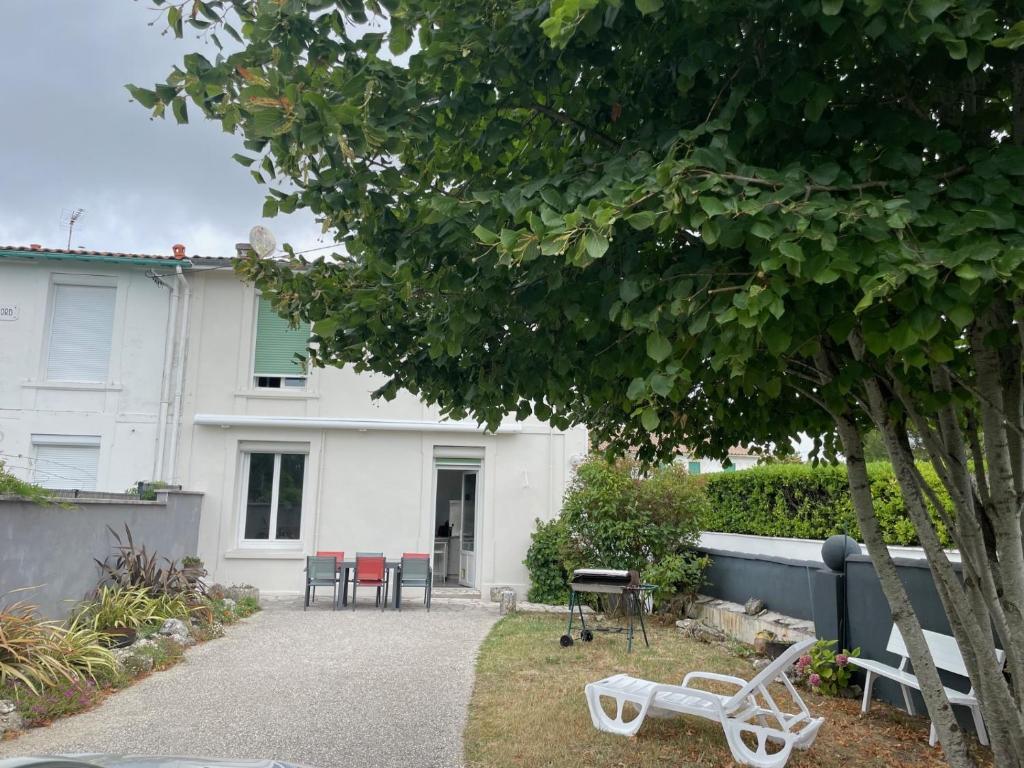 une maison blanche avec des tables et des chaises dans une cour dans l'établissement Maison de vacances calme pour 4-6 personnes, à Saint-Palais-sur-Mer