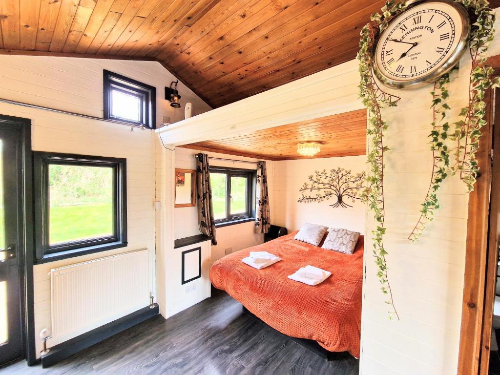 a bedroom in a tiny house with a clock on the wall at Otter 2 HuntersMoon- Warminster-Wiltshire-Bristol in Warminster