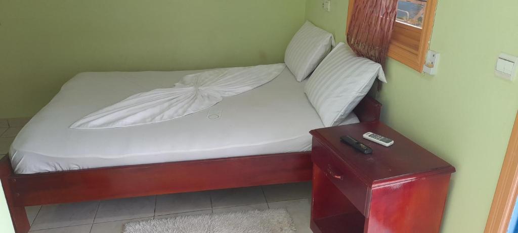 a small bed with white sheets and pillows next to a table at CHEZLIBAMA in Franceville