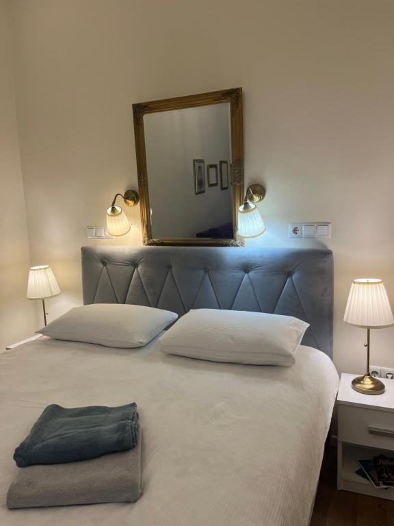 een slaapkamer met een bed met een spiegel en 2 lampen bij Aria Apartments Sarajevo in Sarajevo