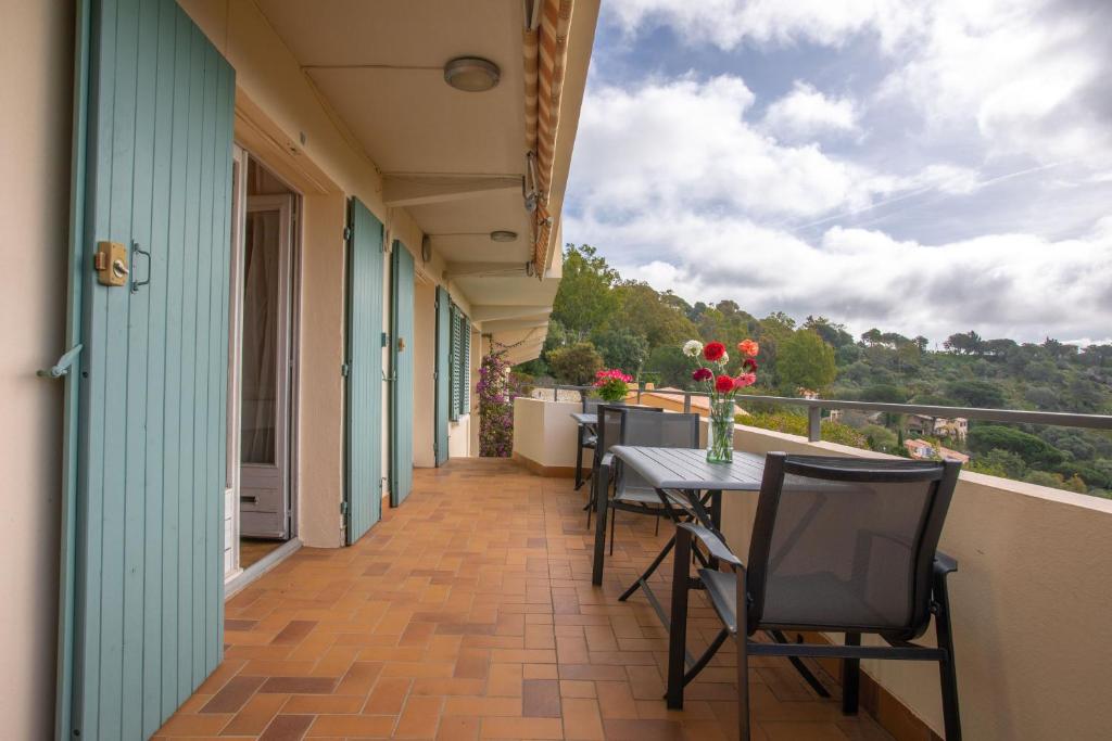 d'un balcon avec des chaises et une table fleurie. dans l'établissement Le Mas Berliat studio N° 10, à Bormes-les-Mimosas
