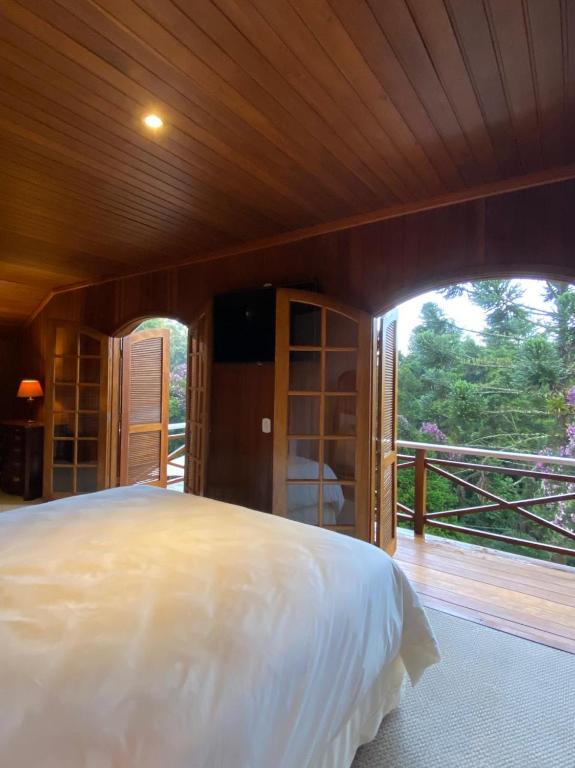 um quarto com uma cama grande e uma janela grande em Tília Pousada de Charme em Campos de Jordão